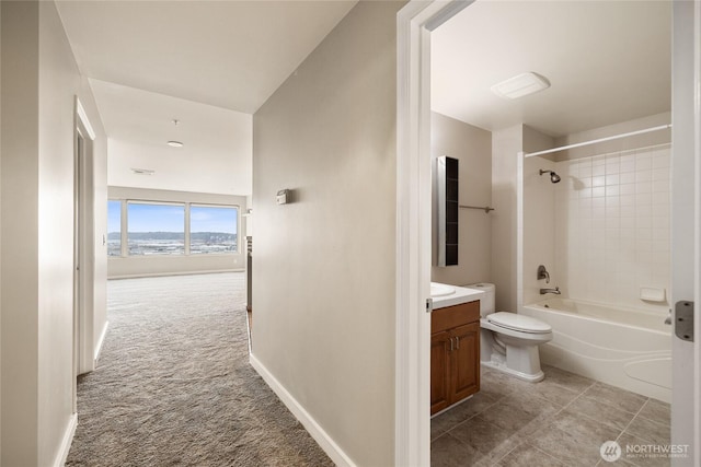 bathroom featuring toilet, vanity, baseboards, and tub / shower combination