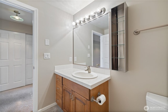 bathroom with vanity, baseboards, and toilet