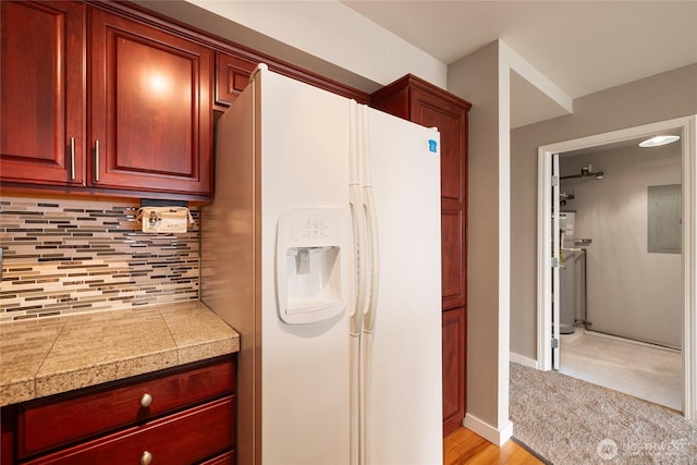 kitchen featuring tile countertops, white fridge with ice dispenser, backsplash, and dark brown cabinets
