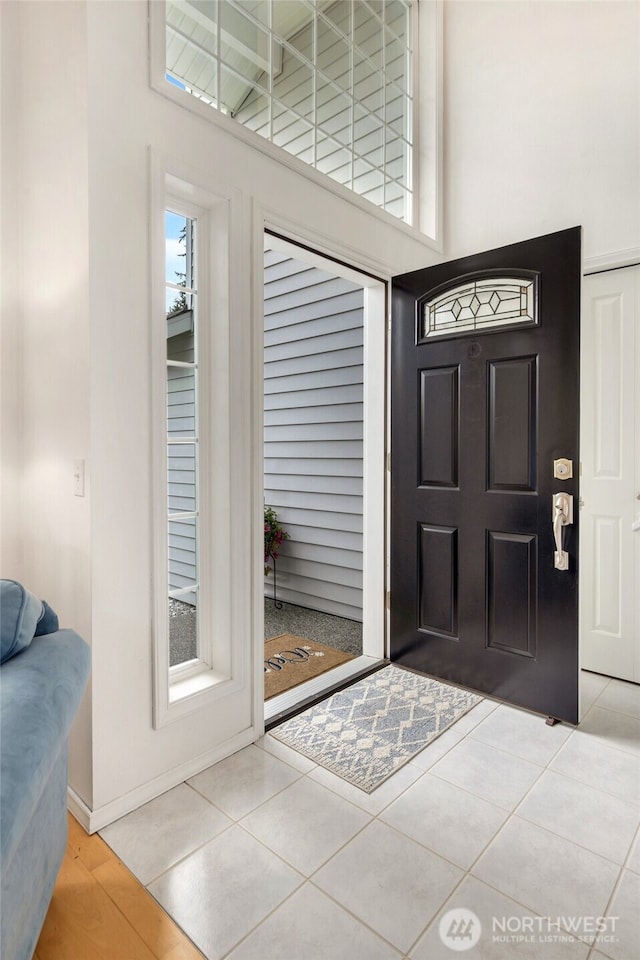 tiled entrance foyer with a high ceiling and baseboards