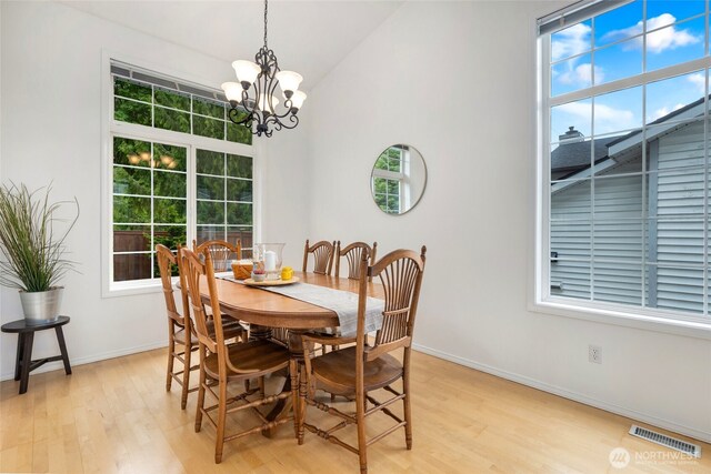 dining space featuring a chandelier, light wood-type flooring, baseboards, and high vaulted ceiling