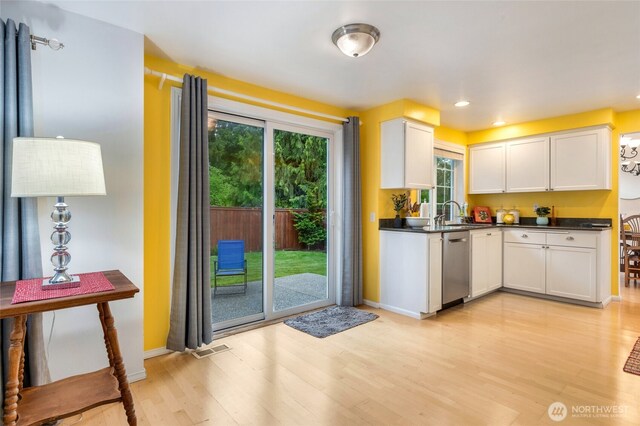kitchen with dark countertops, dishwasher, light wood finished floors, white cabinets, and recessed lighting