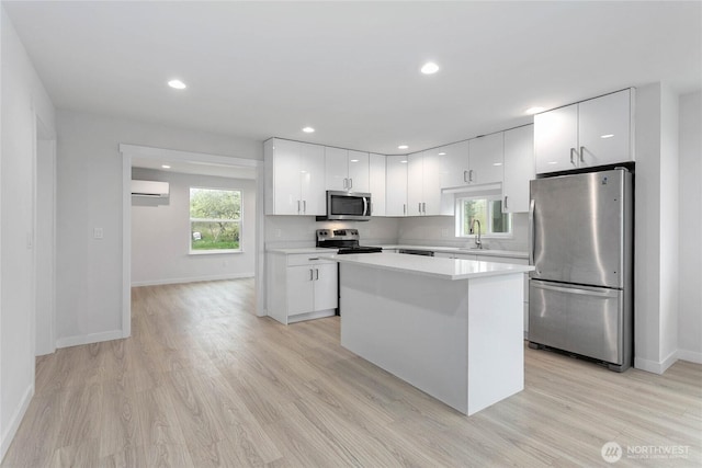 4656 Bay Rd, Blaine, WA 98230 - kitchen featuring white cabinets, a kitchen island, light countertops, an AC wall unit, and stainless steel appliances