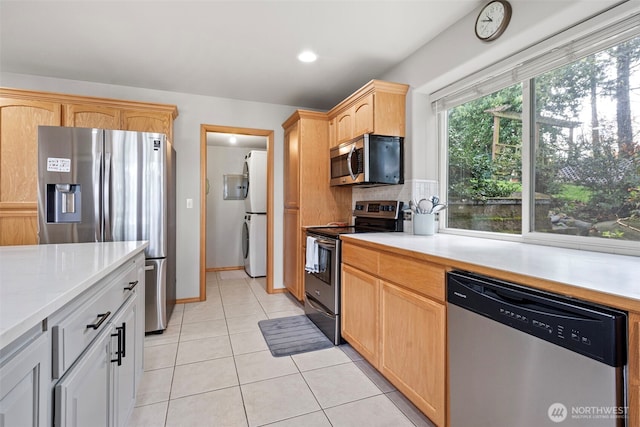 1716 7th St SE, Puyallup, WA 98372 - kitchen with stacked washer / dryer, appliances with stainless steel finishes, light tile patterned flooring, light countertops, and light brown cabinets
