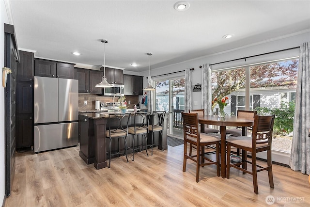 dining space with recessed lighting, ornamental molding, and light wood finished floors