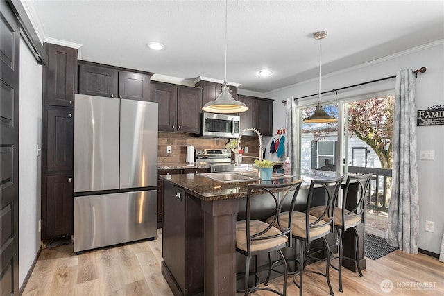 kitchen featuring light wood-style floors, appliances with stainless steel finishes, crown molding, and a sink