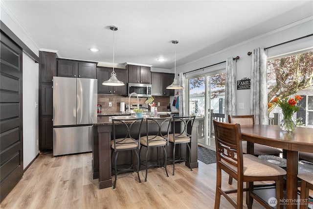 kitchen featuring appliances with stainless steel finishes, decorative backsplash, ornamental molding, and a kitchen bar