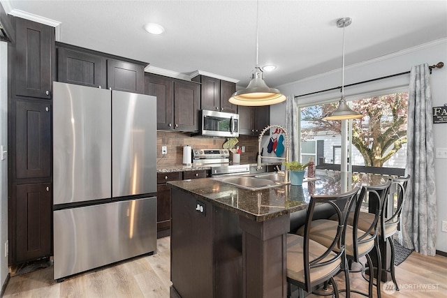 kitchen featuring crown molding, light wood-style flooring, tasteful backsplash, and stainless steel appliances