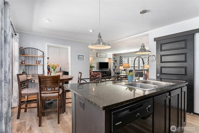 kitchen with crown molding, a sink, dishwasher, light wood-style flooring, and a center island with sink