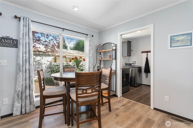 dining room with washer and dryer, light wood-style flooring, baseboards, visible vents, and ornamental molding