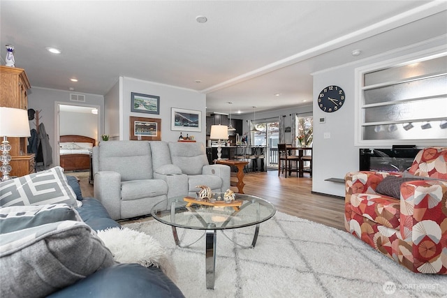 living area featuring crown molding, recessed lighting, wood finished floors, and visible vents