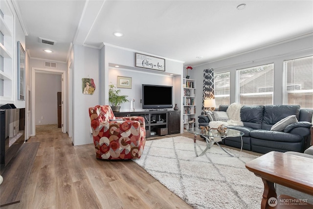 living area with crown molding, recessed lighting, wood finished floors, and visible vents