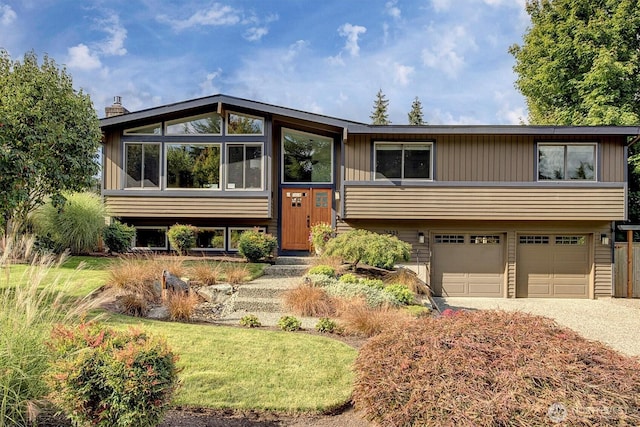 raised ranch with gravel driveway and an attached garage