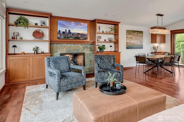 sitting room with recessed lighting, a tiled fireplace, light wood finished floors, and baseboards