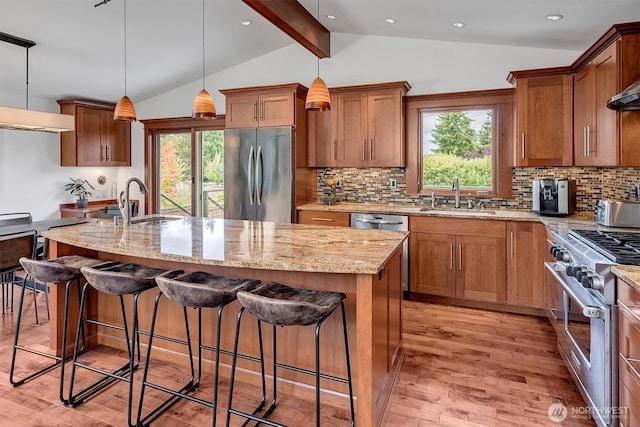 kitchen with light stone counters, lofted ceiling with beams, light wood-style flooring, stainless steel appliances, and a sink