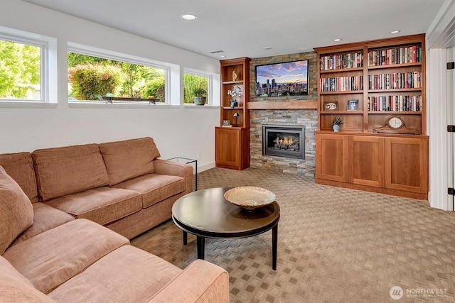 living room featuring recessed lighting, carpet, a stone fireplace, and baseboards