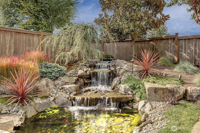 view of yard featuring a fenced backyard and a garden pond