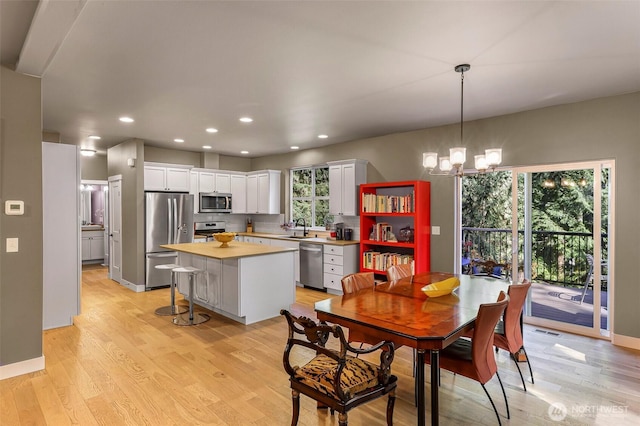 dining area with light wood-type flooring, visible vents, recessed lighting, a notable chandelier, and baseboards