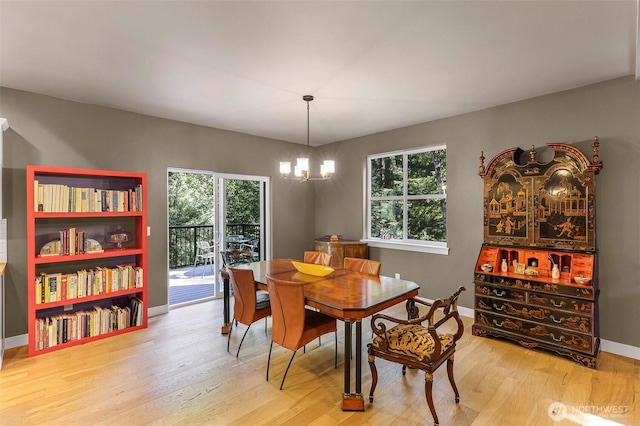 dining area with light wood finished floors, an inviting chandelier, and plenty of natural light