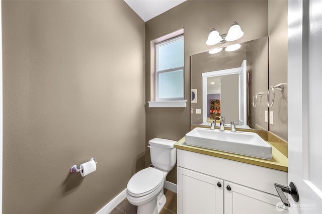half bathroom featuring toilet, baseboards, and vanity