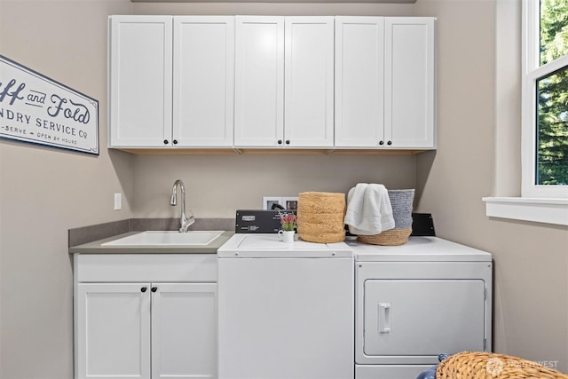 laundry room featuring washing machine and dryer, cabinet space, and a sink