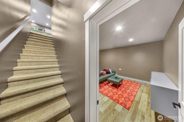 stairway with wood finished floors, baseboards, and recessed lighting