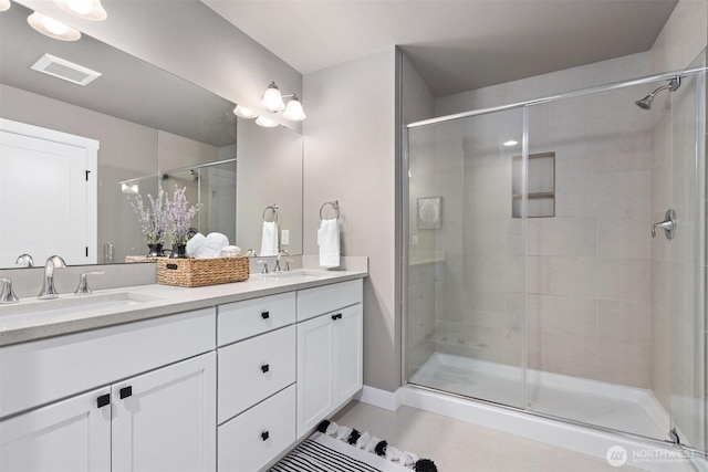 full bathroom with a stall shower, visible vents, a sink, and double vanity