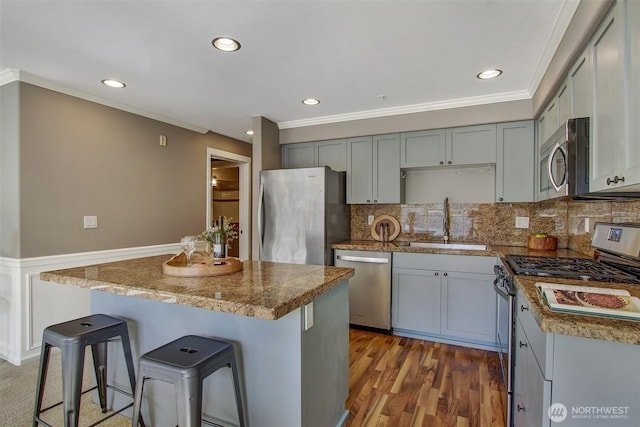 10549 Stone Ave N Unit 103, Seattle, WA 98133 - kitchen with appliances with stainless steel finishes, a kitchen breakfast bar, a center island, ornamental molding, and decorative backsplash