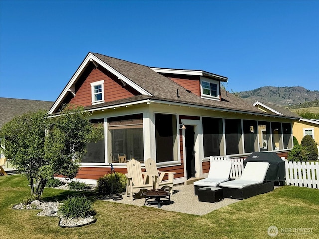back of property featuring a mountain view, a sunroom, fence, a lawn, and a shingled roof
