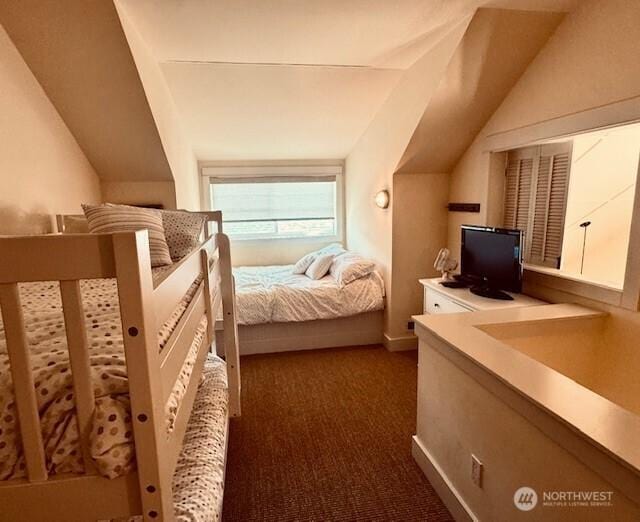 carpeted bedroom with lofted ceiling and baseboards