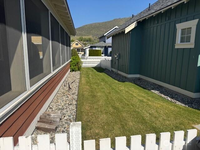view of yard with fence, a sunroom, and a mountain view