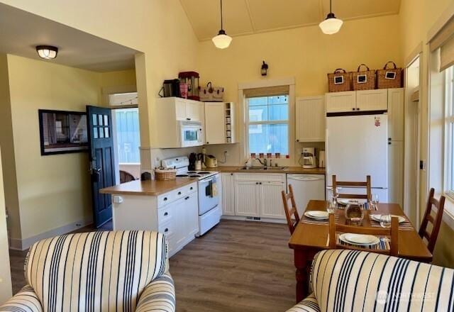 kitchen with pendant lighting, white cabinetry, dark wood-type flooring, white appliances, and lofted ceiling