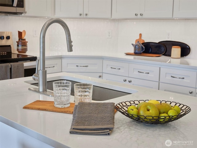 303 Kakela Rd, Winlock, WA 98596 - kitchen view of stainless steel appliances, backsplash, a sink, and white cabinets