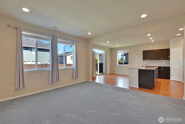 kitchen with light colored carpet, open floor plan, a sink, and recessed lighting