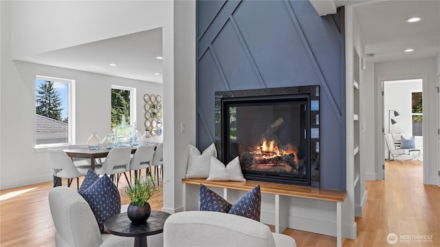 interior details with baseboards, recessed lighting, a glass covered fireplace, and wood finished floors