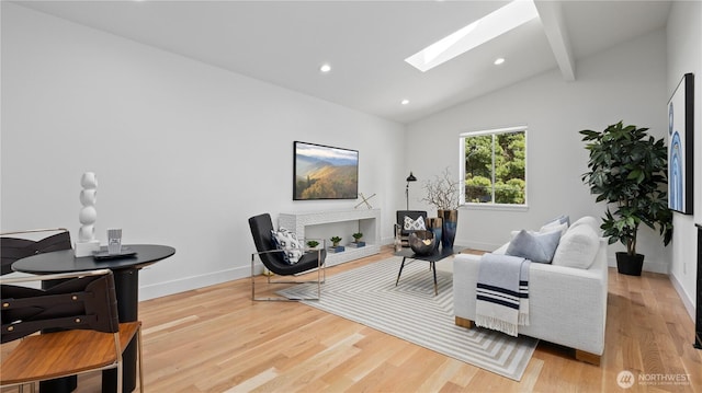 living area featuring vaulted ceiling with skylight, baseboards, and wood finished floors
