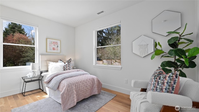 bedroom with visible vents, baseboards, and wood finished floors