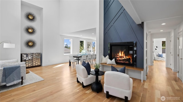 sitting room featuring a premium fireplace, a wealth of natural light, and light wood-style flooring
