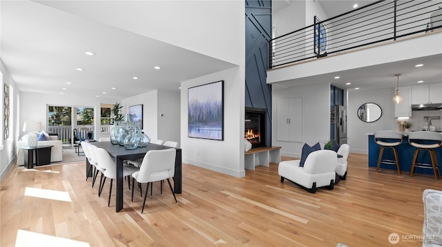 dining room with light wood finished floors, a lit fireplace, and baseboards