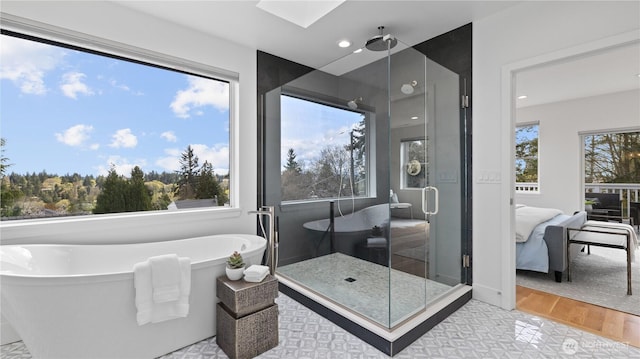 bathroom featuring a stall shower, a soaking tub, connected bathroom, a skylight, and wood finished floors