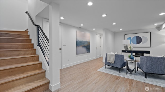 living room with light wood finished floors, baseboards, recessed lighting, and stairs