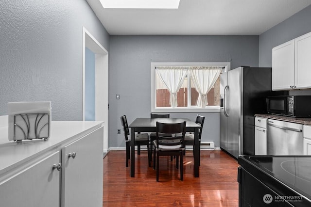 dining space with dark wood-type flooring, a skylight, and a textured wall