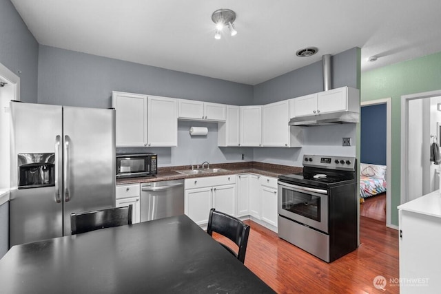 kitchen featuring visible vents, a sink, appliances with stainless steel finishes, under cabinet range hood, and white cabinetry