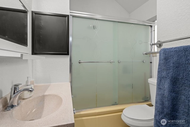 bathroom featuring combined bath / shower with glass door, vanity, and toilet