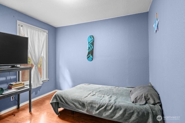 bedroom with baseboards and wood finished floors