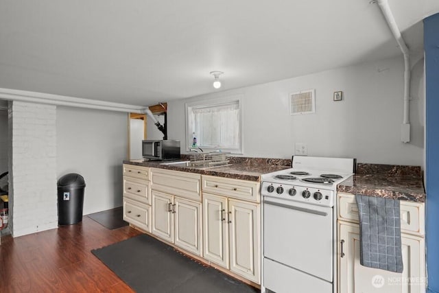 kitchen featuring visible vents, a sink, cream cabinetry, stainless steel microwave, and electric range