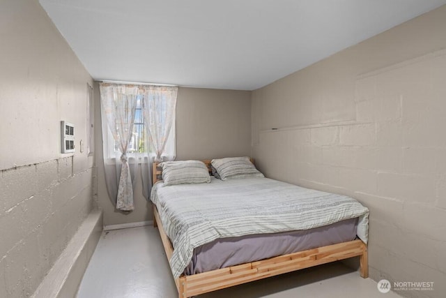 bedroom with finished concrete flooring, visible vents, and concrete block wall