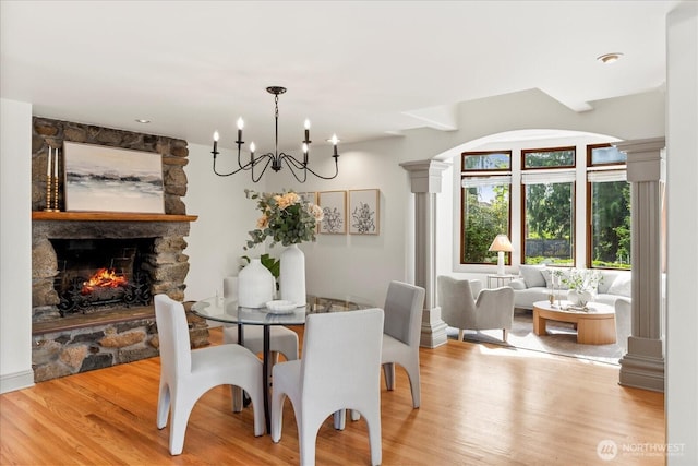 21908 36th Ave W, Brier, WA 98036 - dining space featuring light wood finished floors, ornate columns, a stone fireplace, and a chandelier