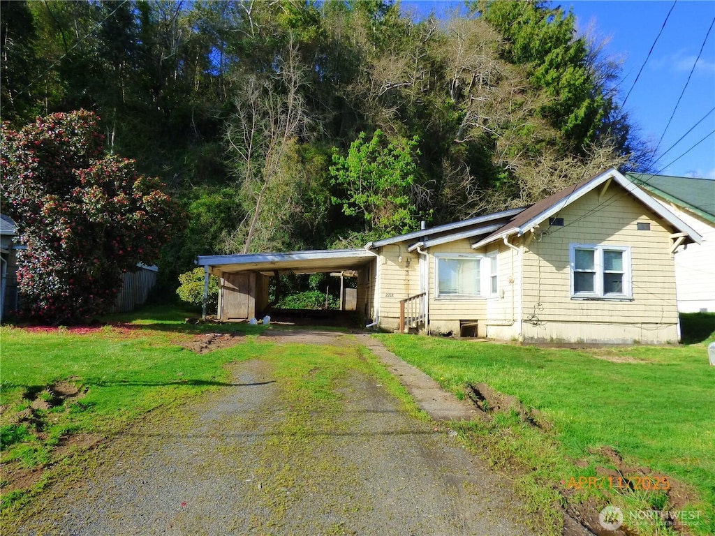 ranch-style house featuring a carport, driveway, and a front lawn
