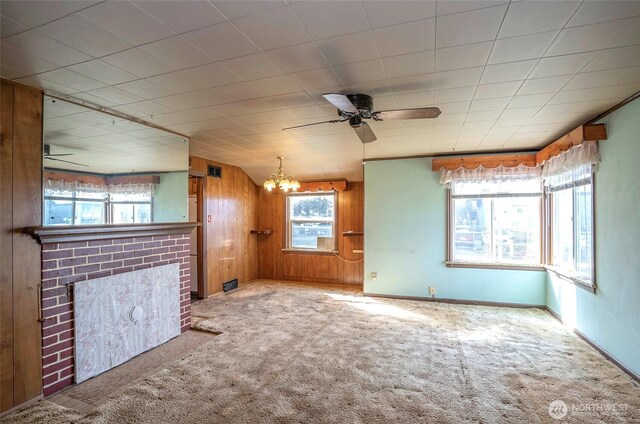 1257 S Ridgewood Ave, Tacoma, WA 98405 - unfurnished living room with carpet floors, wood walls, a fireplace, and ceiling fan with notable chandelier